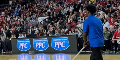PPC staff cleaning the basketball court during a Calgary Surge game, with Picture Perfect Cleaning logos on the LED boards.